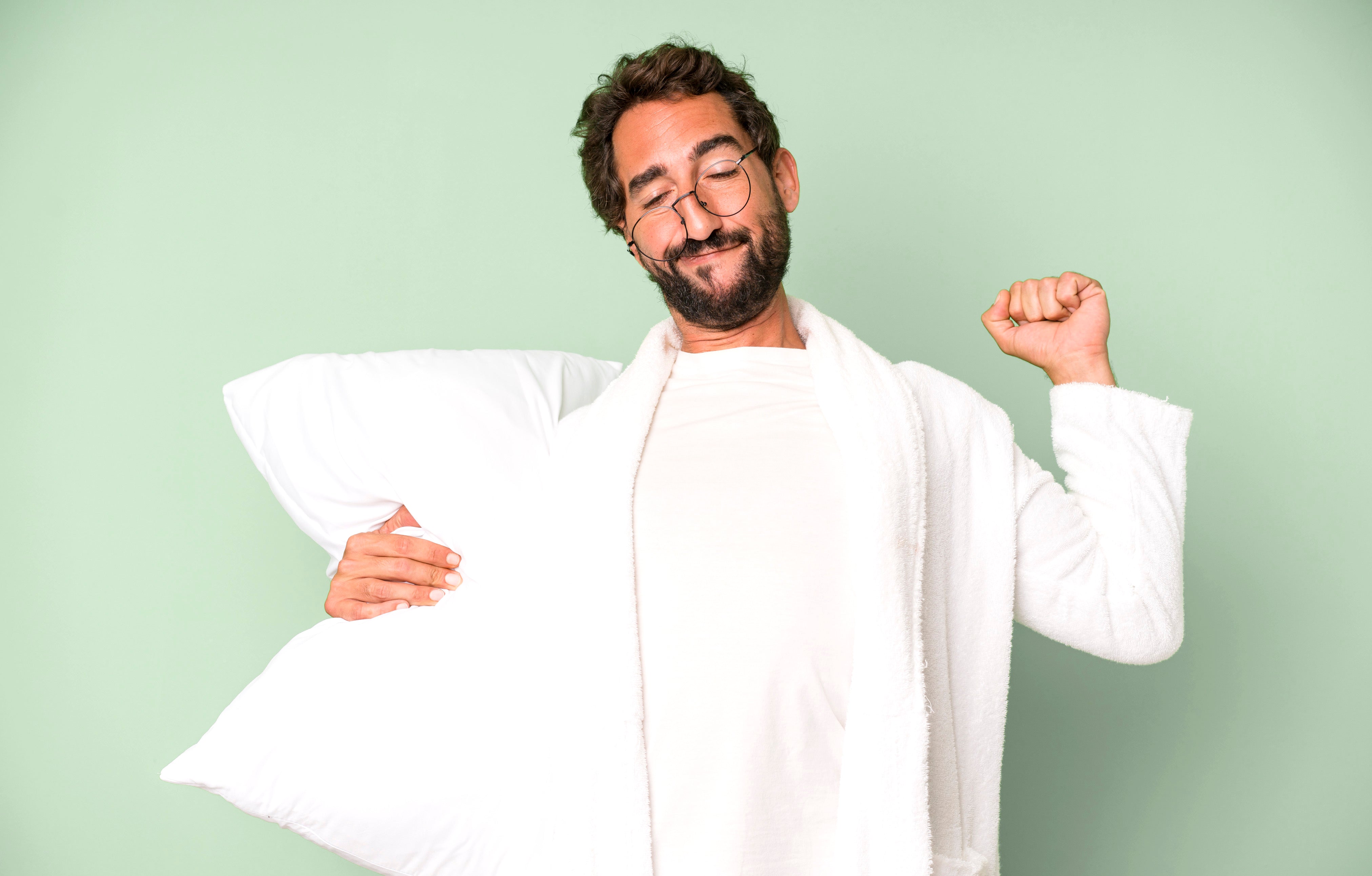 Man in a bathrobe holding a pillow, highlighting the importance of good sleep for mental wellbeing, as discussed by The Vitalogy Project.